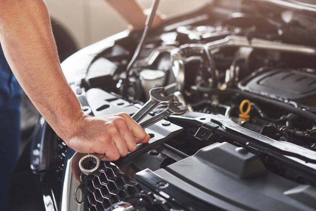 muscular-car-service-worker-repairing-vehicle